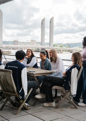 Groupe d’étudiants assis autour d’une table sur la terrasse en bord de Garonne du campus de Bordeaux de l’école de commerce INSEEC